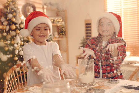 Cute little children having fun while making delicious Christmas cookies at homeの写真素材