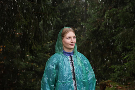Young woman with raincoat in forest under rainの写真素材