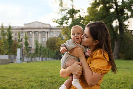 Happy mother with adorable baby walking in park on sunny day, space for textの写真素材