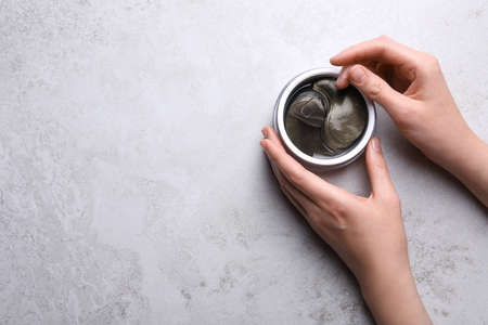 Woman with package of under eye patches at light table, top view and space for text. Cosmetic productの写真素材