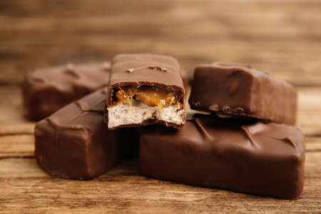 Chocolate bars with caramel, nuts and nougat on wooden table, closeupの写真素材