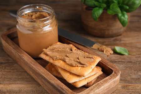 Crispy crackers with delicious meat pate on wooden table