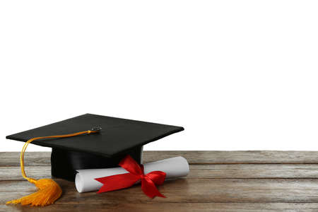 Graduation hat and diploma on wooden table against white background, space for textの写真素材