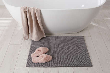 Soft gray bath mat and slippers on floor in bathroomの写真素材