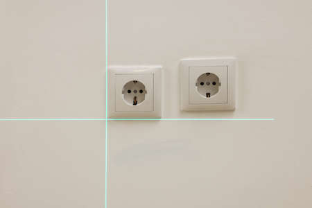 Using cross line laser level for accurate installation of outlet in white wall