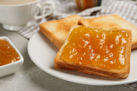 Toast with tasty orange jam and roasted slices of bread on table, closeupの写真素材