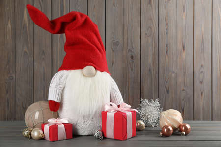 Cute Christmas gnome, gift boxes and festive decor on wooden table. Space for textの写真素材