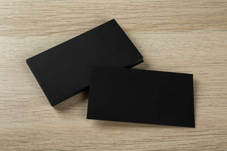 Blank black business cards on wooden background, above view. Mockup for designの写真素材