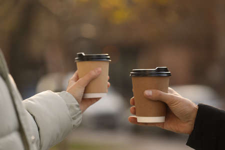 Couple with takeaway coffee cups outdoors, closeupの写真素材