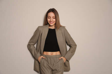 Portrait of beautiful young woman in fashionable suit on gray background. Business attireの写真素材