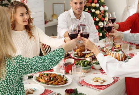 Happy family with their friends clinking glasses at festive dinner indoors. Christmas eve celebrationの写真素材