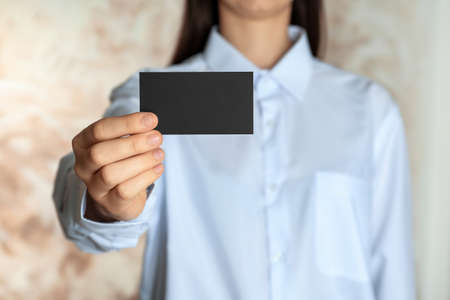 Woman holding blank business card on blurred background, closeup. Mockup for designの写真素材