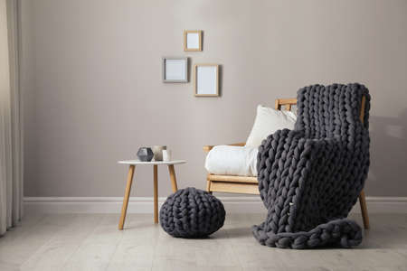 Soft chunky knit blanket on armchair in room. Interior designの写真素材