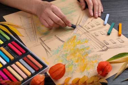 Woman drawing beautiful building with soft pastel at wooden table, closeupの写真素材