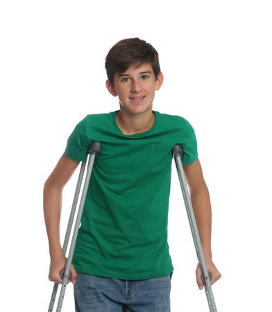 Teenage boy with injured leg using crutches on white backgroundの写真素材