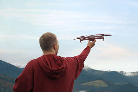Young man with modern drone in mountains, back viewの写真素材