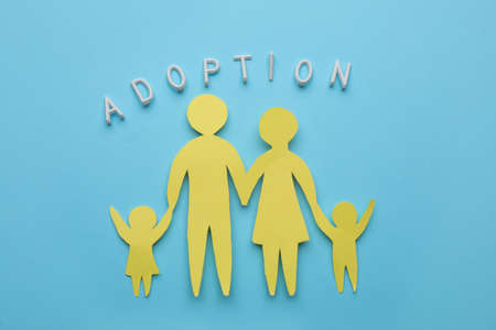 Family figure and word Adoption on light blue background, flat layの写真素材