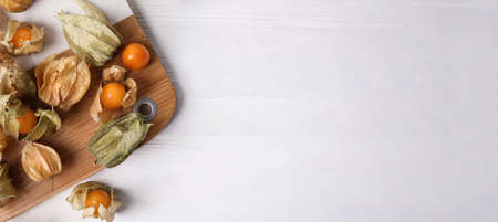 Ripe physalis fruits on white wooden table, flat lay with space for text. Banner designの写真素材