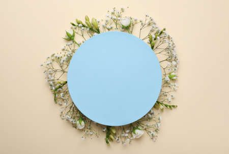 Blank card with gypsophila, roses and freesia flowers on beige background, top view. Space for textの写真素材
