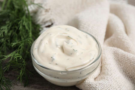 Tasty creamy sauce and fresh dill on wooden table, closeupの写真素材