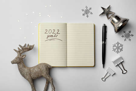 Inscription 2022 Goals written in planner and Christmas decor on white background, flat lay. New...