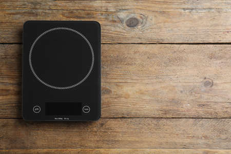 Modern digital kitchen scale on wooden table, top view. Space for textの写真素材