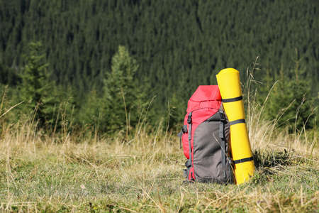 Backpack with sleeping mat on grassy hill, space for text. Mountain tourismの写真素材