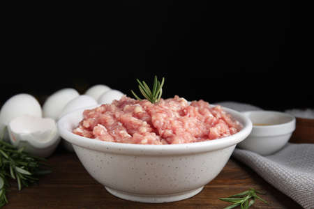 Raw chicken minced meat with rosemary on wooden tableの写真素材