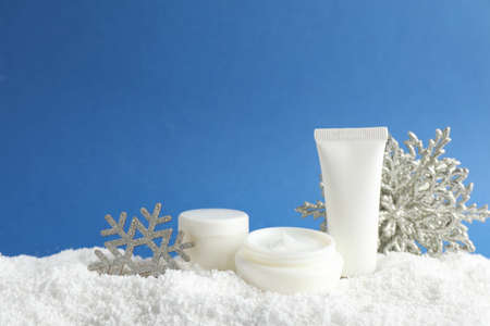 Set of winter skin care cosmetics with hand cream and decorative snowflakes on snow against blue background. Space for textの写真素材