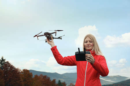 Young woman with modern drone in mountainsの写真素材