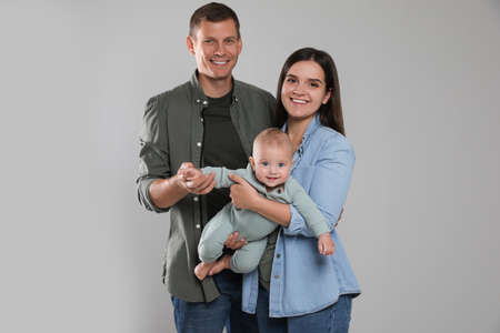 Happy family. Couple with their cute baby on gray background