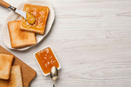 Toasts and orange jam served on white wooden table, flat lay. Space for textの写真素材