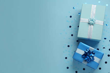 Gift boxes and shiny confetti on light blue background, flat lay. Space for text