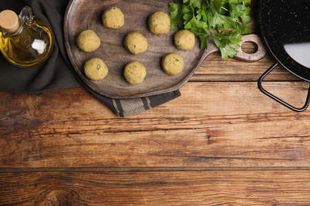 Raw falafel balls and ingredients on wooden table, flat lay. Space for textの写真素材