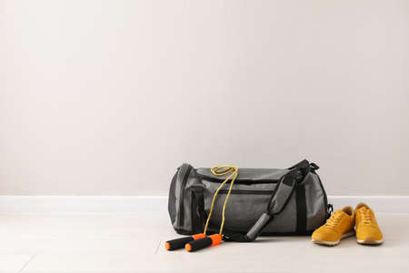 Gray bag and sports accessories on floor near light wall, space for textの写真素材