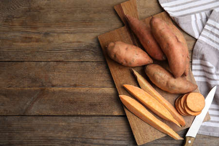 Sweet potatoes and knife on wooden table, flat lay. Space for textの写真素材