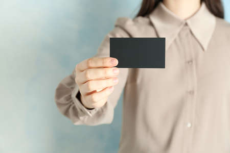 Woman holding blank business card on light blue background, closeup. Mockup for designの写真素材