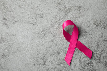 Pink ribbon on gray table, top view with space for text. Breast cancer awareness conceptの写真素材