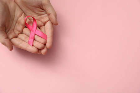 Woman holding pink ribbon on color background, top view with space for text. Breast cancer awareness conceptの写真素材