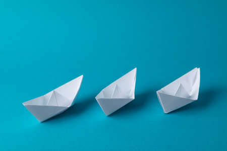 Handmade white paper boats on light blue background. Origami artの写真素材