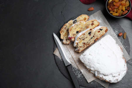 Traditional Christmas Stollen with icing sugar on black table, flat lay. Space for textの写真素材