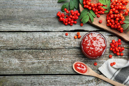 Delicious rowan jam and berries on wooden table, flat lay. Space for textの写真素材