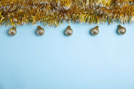Golden tinsel and Christmas balls on light blue background, flat lay. Space for textの写真素材
