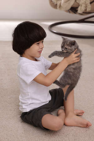 Cute little boy with kitten on floor at home. Childhood petの写真素材