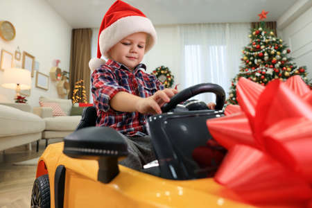 Cute little boy driving toy car in room decorated for Christmasの写真素材