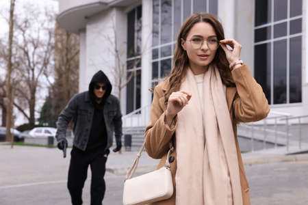 Man with gun stalking young woman on city streetの写真素材