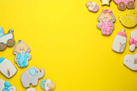 Cute tasty cookies of different shapes on yellow background, flat lay with space for text. Baby...
