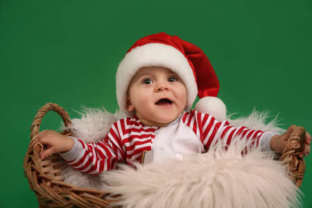Cute baby in wicker basket on green background. Christmas celebrationの写真素材