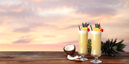 Tasty Pina Colada cocktail on wooden table at sunset, space for text. Banner design