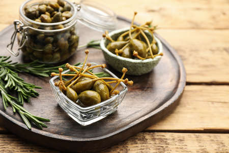 Delicious pickled capers and rosemary on wooden tableの写真素材